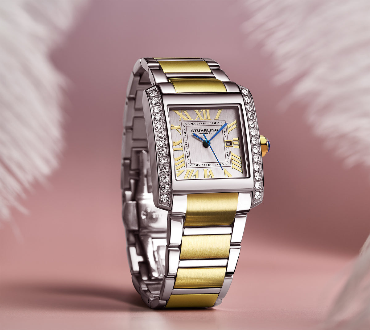 Gold and silver watch with diamond accents on a pink background