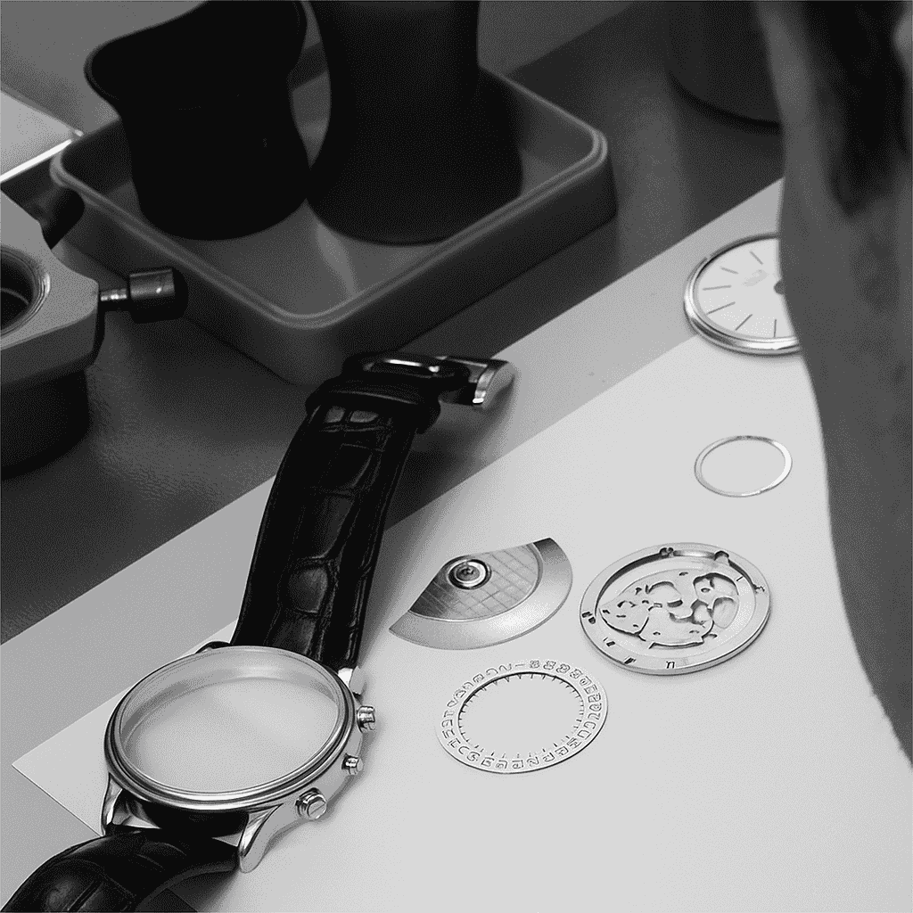 Watch components on a table with a focus on watchmaking tools and parts.
